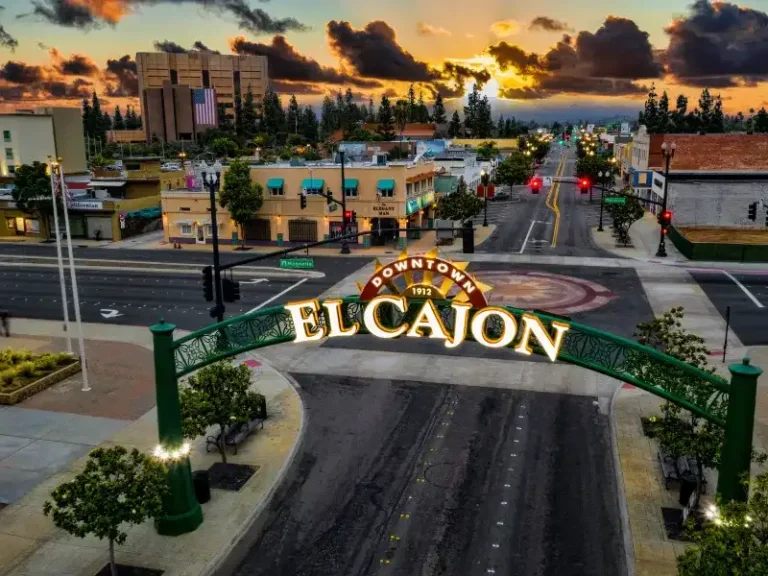 Downtown El Cajon archway over a street at sunset with buildings and trees in the background